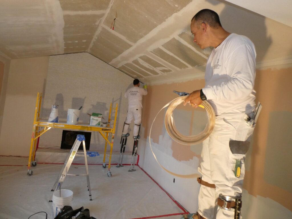 2 workmen installing drywall in an attic